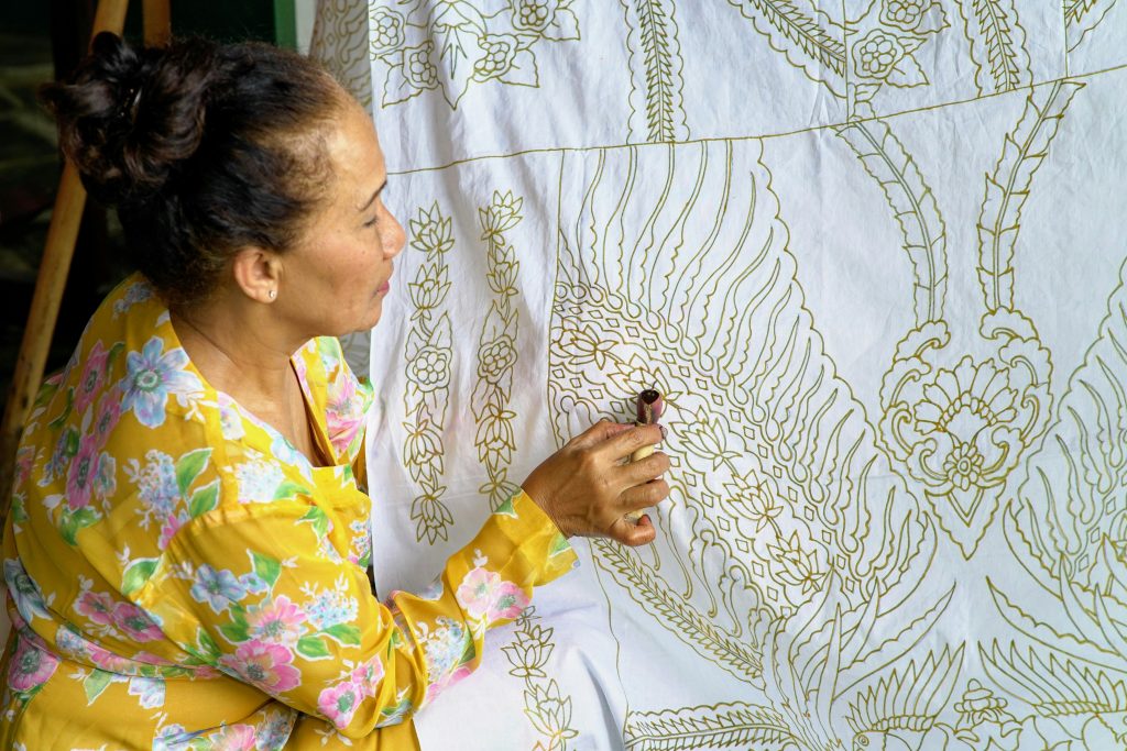 Craftswoman making intricate batik patterns on fabric in West Java, Indonesia.
